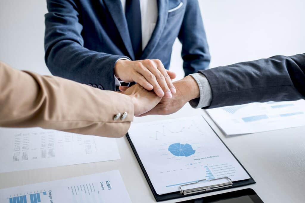 Image of business people joining and putting hands together during their meeting