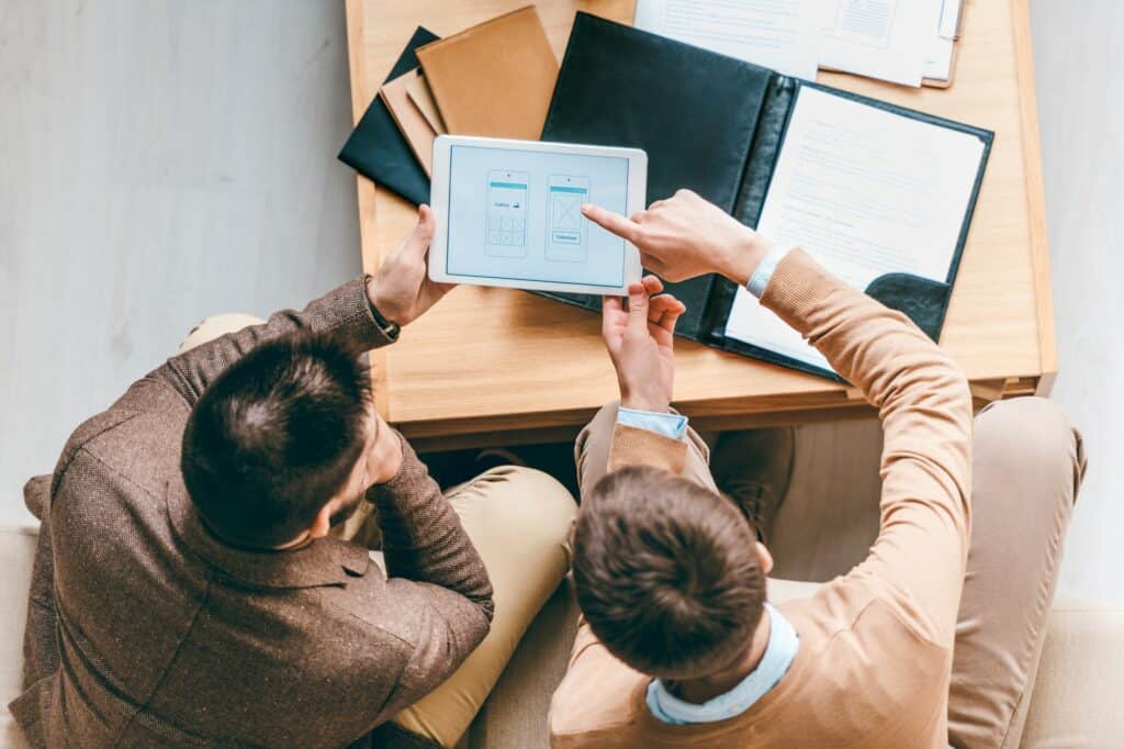 Top view of two young businessmen discussing new software for smartphones